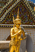 Golden statue of a Singhaphanon mythical creature guards the Phra Wiharn Yod in the Grand Palace complex in Bangkok, Thailand. A Singhaphanon has the upper body of a monkey and lower body of a lion.