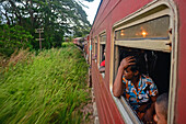 Menschen schauen durch ein offenes Zugfenster, Sri Lanka