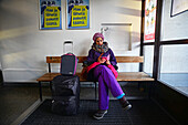 Junge Frau benutzt ihr Handy, während sie auf den Bus im Bahnhof von Kemi, Lappland, wartet