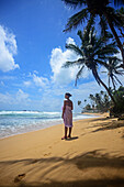 Junge Frau beim Spaziergang am Strand von Hikkaduwa bei Sonnenuntergang, Sri Lanka