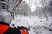 Antti, junger finnischer Reiseleiter von VisitInari, fährt mit einem Schneemobil in der Wildnis von Inari, Lappland, Finnland