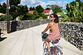 Junge Frau fährt Fahrrad auf der Insel Taketomi, Präfektur Okinawa, Japan