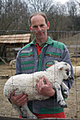 Rancher holding lamb for tourists to see and touch.