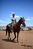 Niedliches junges Indianermädchen reitet auf ihrem Pferd während der Navajo Nation Fair, einer weltbekannten Veranstaltung, bei der die Landwirtschaft, die Kunst und das Kunsthandwerk der Navajo vorgestellt und das kulturelle Erbe der Navajo durch kulturelle Unterhaltung gefördert und bewahrt wird. Window Rock, Arizona