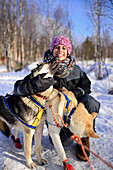 Junge Frau erhält Liebe von freundlichen Hunden. Wildnis-Husky-Schlittentour in der Taiga mit Bearhillhusky in Rovaniemi, Lappland, Finnland