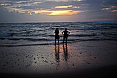 Zwei Frauen entspannen sich bei Sonnenuntergang am Strand von Hikkaduwa, Sri Lanka