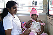 Young woman holding baby in bus, Sri Lanka