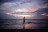 Junge Frau genießt den Sonnenuntergang am Strand von Hikkaduwa, Sri Lanka