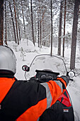 Antti, junger finnischer Reiseleiter von VisitInari, fährt mit einem Schneemobil in der Wildnis von Inari, Lappland, Finnland