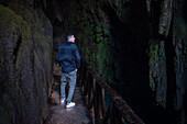 Junger Mann in einer Höhle im Naturpark Monasterio de Piedra, der sich um das Monasterio de Piedra (Steinkloster) in Nuevalos, Zaragoza, Spanien, erstreckt