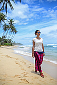 Junge Frau beim Spaziergang am Strand zwischen Weligama und Ahangama, Sri Lanka