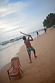 Junge Männer spielen Kricket am Strand von Hikkaduwa, Sri Lanka