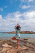 Young attractive brunette doing yoga in Formentera