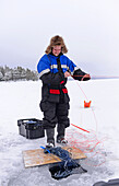 Fisherman practicing ice fishing in Lake Inari, Lapland, Finland