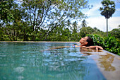 Young attractive woman enjoying a bath in the infinity edge swimming pool at The Dutch House, Galle, Sri Lanka