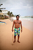 Portrait of young man holding a cricket stick on the beach, Hikkaduwa, Sri Lanka