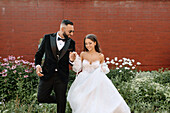 Bride and groom walking on sidewalk in town