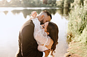 Bride and groom embracing on lakeshore