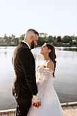 Braut und Bräutigam schauen sich am Seeufer in die Augen
