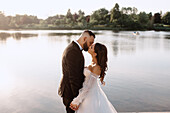 Bride and groom kissing on lakeshore