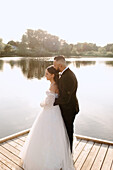 Bride and groom embracing on lakeshore