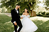 Happy bride and groom holding hands in park