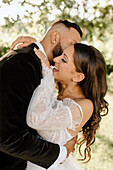 Bride and groom embracing in park