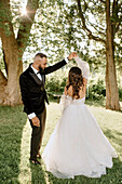 Bride and groom dancing in park