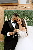 Bride and groom holding champagne glasses and kissing