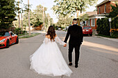 Rear view of bride and groom walking on suburban street