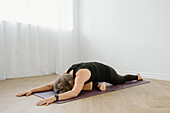 Frau in Taubenstellung auf Yogamatte zu Hause