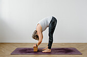Woman practicing yoga with yoga block on exercise mat