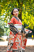 Porträt einer lächelnden Frau im Kimono im Park