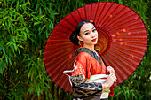 Portrait of smiling woman wearing kimono and holding parasol