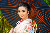Porträt einer lächelnden Frau mit Kimono und Sonnenschirm in der Hand