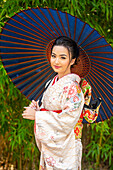 Porträt einer lächelnden Frau mit Kimono und Sonnenschirm in der Hand