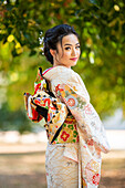 Porträt einer lächelnden Frau in Kimono im Park