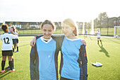 UK, Porträt von weiblichen Fußballspielern (10-11, 12-13), die sich auf dem Feld umarmen