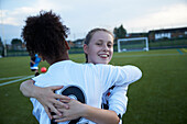 UK, Weibliche Fußballspielerinnen (10-11, 12-13) umarmen sich auf dem Feld