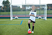 UK, Portrait of smiling female soccer player (12-13) in front of goal