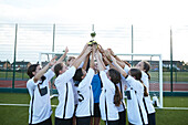 UK, Mädchen-Fußballmannschaft (10-11, 12-13) hält Trophäe im Fußballfeld
