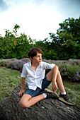 Nachdenklicher Junge (8-9) sitzt in einem Lavendelfeld
