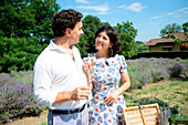 Lächelndes reifes Paar beim Picknick in einem Lavendelfeld