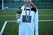 UK, Fußballspielerin (10-11) mit Goldmedaille und Trophäe auf dem Feld