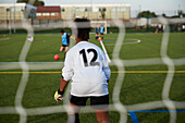 UK, Rear view of female soccer goalie (12-13) defending goal