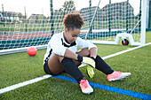 UK, Rückansicht einer weiblichen Fußballtorhüterin (12-13), die ein Tor verteidigt