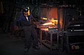 Forge worker pre heating steel billet for forging in upsetter