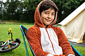 Porträt eines Jungen, der vor einem Zelt sitzt