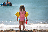 Rear view of girl wearing water wings on beach