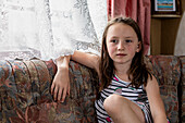 Porträt eines Mädchens (4-5), das auf dem Sofa im Wohnwagen sitzt